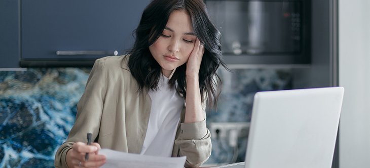 A female small business owner seems overwhelmed by a Schedule C Tax Form she holds in her
	hand, and needs to fill as part of the tax filing process.