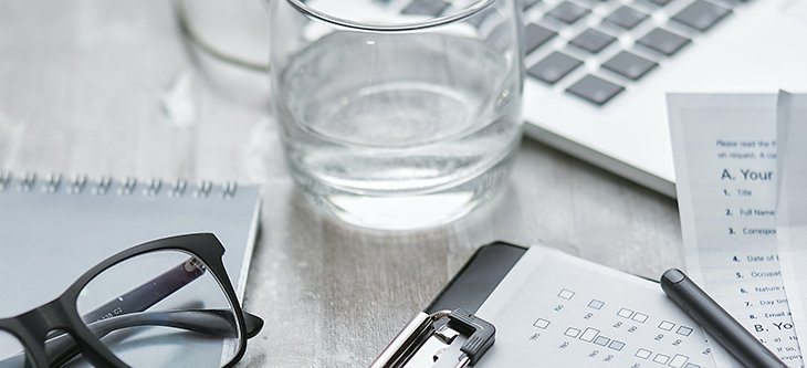 Eyeglasses, a glass of water and legal papers rest beside a computer as a depiction of LegalZoom online legal service -  pexels-mikhail-nilov-7735622