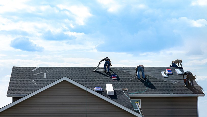 A group of workers install shingles on a residential rooftop with resources acquired thanks to business finance.