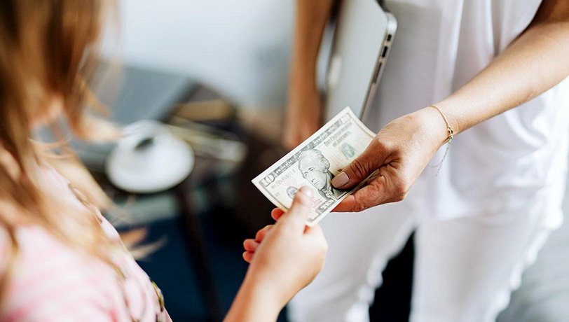 Two women hold a $10 bill to what depicts a payment for medical services as one of them is dressed as a nurse. Photo-by-Karolina-Grabowska-on-Pexels