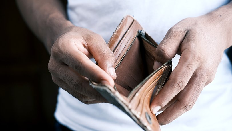 Close up of a man opening an empty wallet depicting a small business owner under a
	financial crisis.